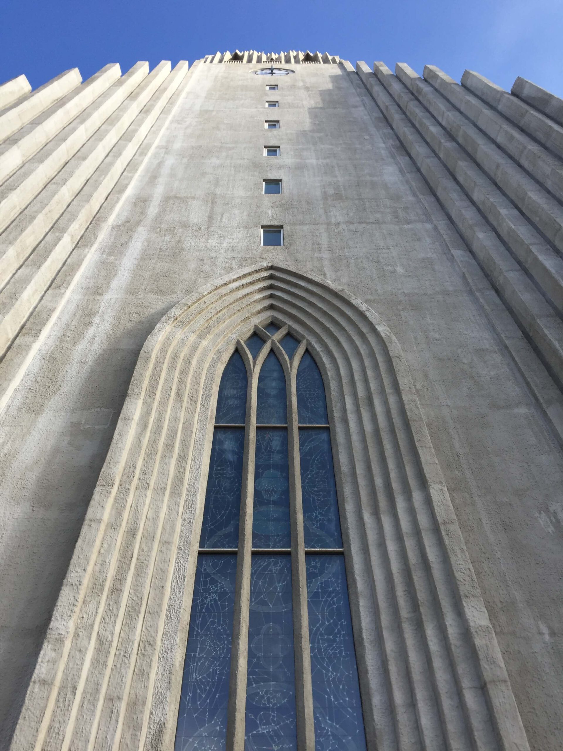 De Hallgrímskirkja in Reykjavík van onderaf gefotografeerd tegen een blauwe lucht