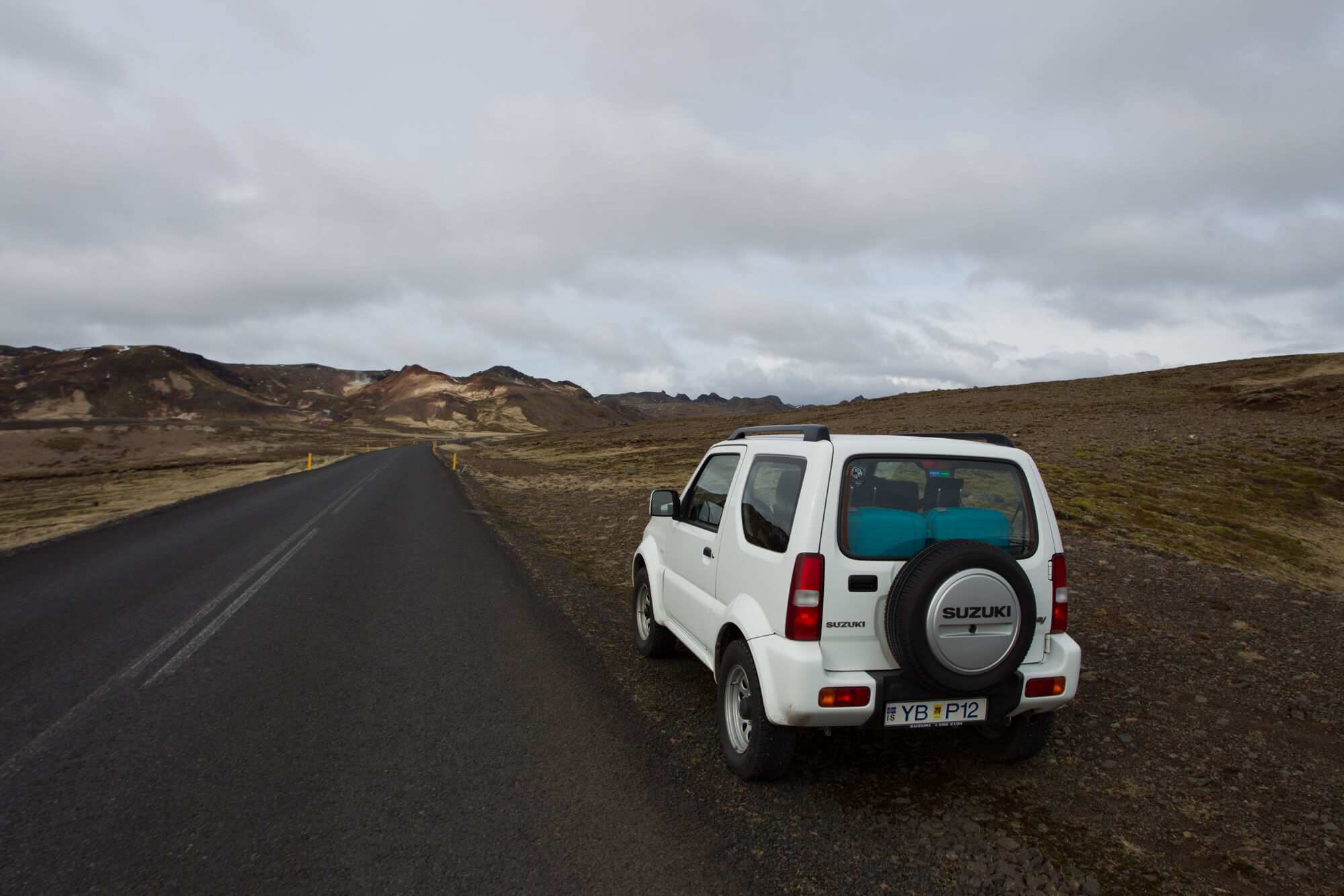 Witte Suzuki Jimny huurauto langs een lege weg op Reykjanes in IJsland