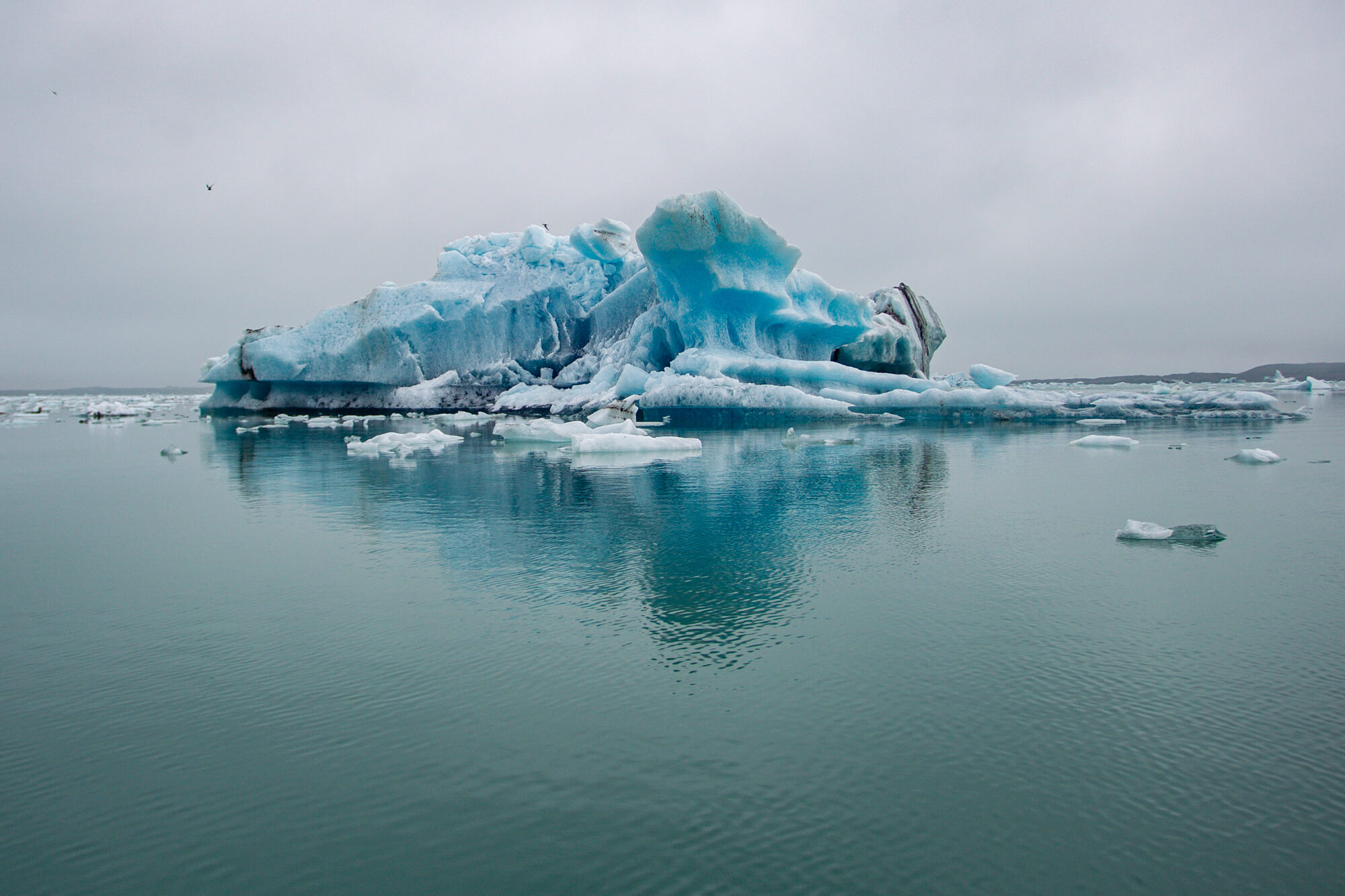Grote blauwe ijsberg drijvend op het gletsjermeer Jökulsárlón met spiegeling in het water