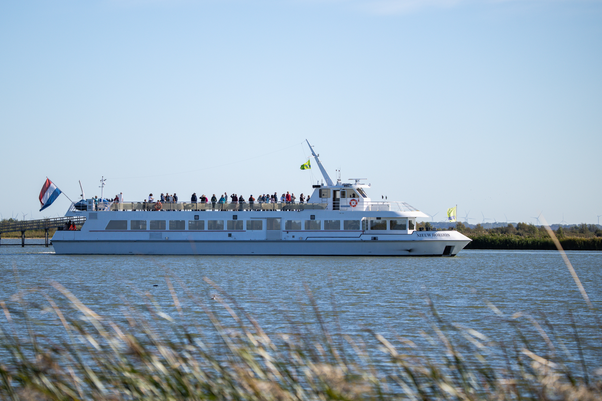 De veerboot Nieuw Horizon met bezoekers op het dek vaart langs de Marker Wadden